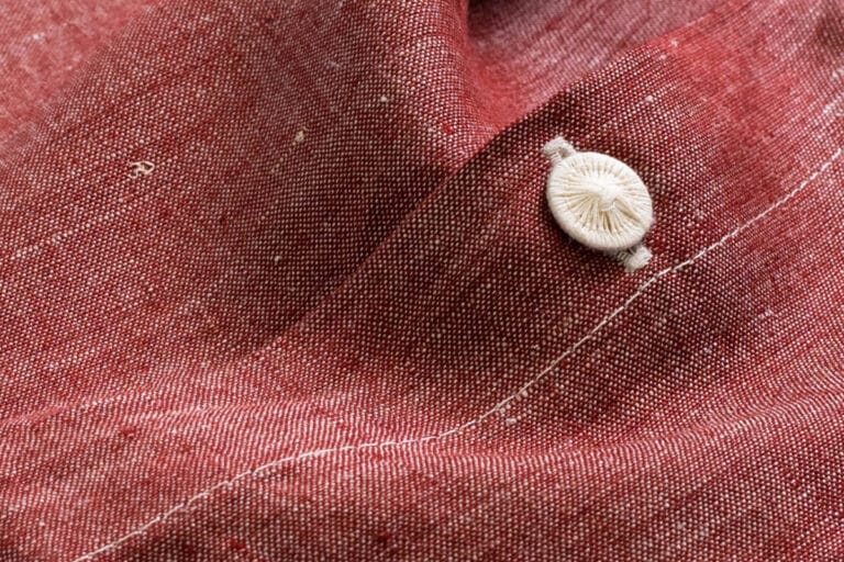 Eine Nahaufnahme eines Knopfes an einem roten Hemd.