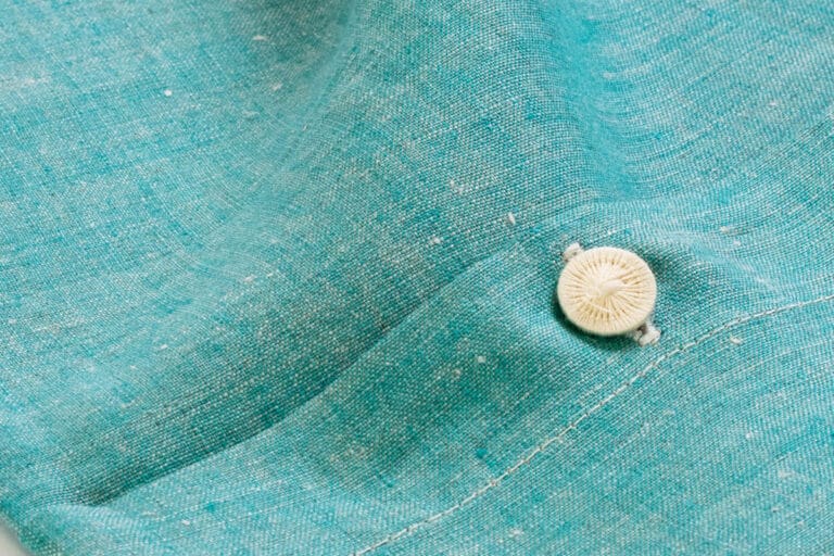 Eine Nahaufnahme eines Knopfes an einem blauen Hemd.