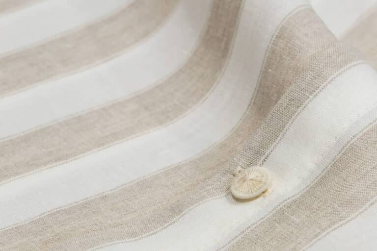 Eine Nahaufnahme eines weiß-beige gestreiften Stoffes.