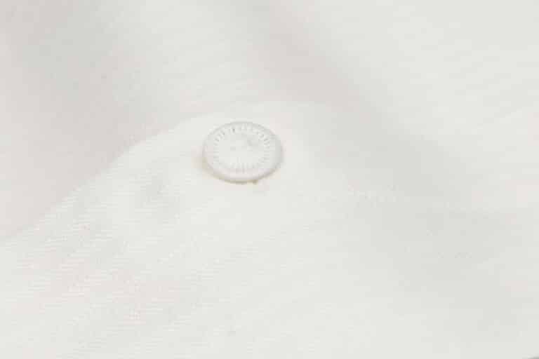 Eine Nahaufnahme eines weißen Hemdes mit einem Knopf.