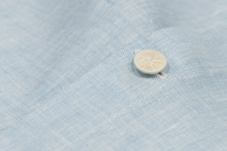 Ein Knopf auf einem hellblauen Leinenstoff.