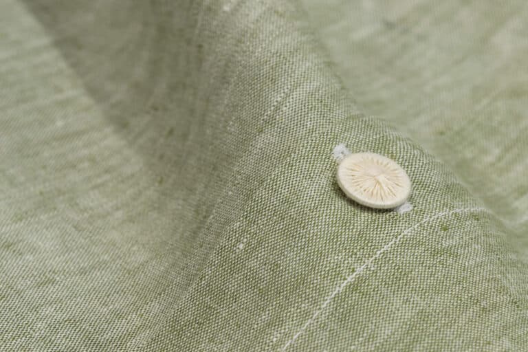 Eine Nahaufnahme eines Knopfes an einem grünen Hemd.