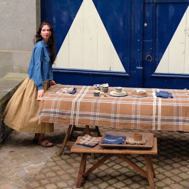 Eine Frau, die neben einem Tisch steht, auf dem ein Tuch liegt.