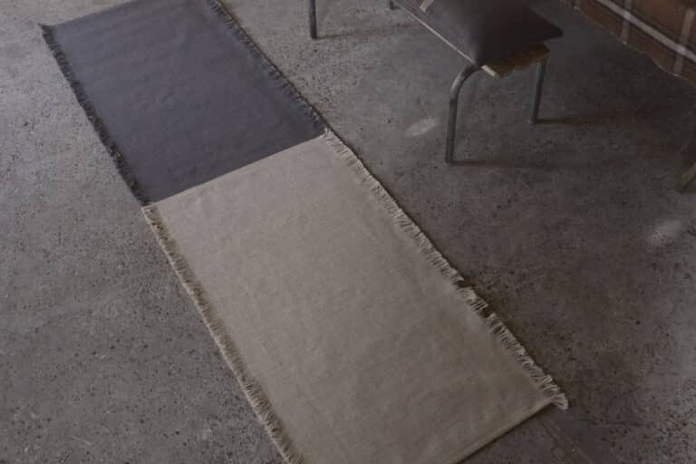 Eine Holzbank, die neben einem Teppich auf dem Boden steht.