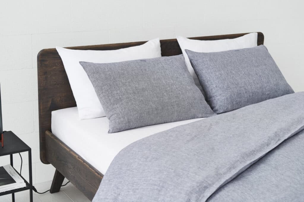Ein Bett mit zwei Kopfkissen und einem Nachttisch.