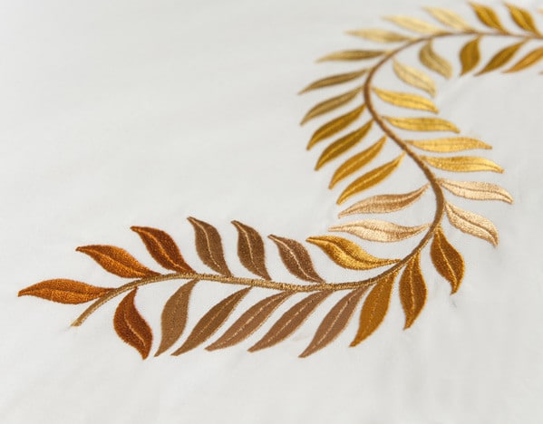 Eine Nahaufnahme eines weißen Lakens mit goldenen Blättern darauf.