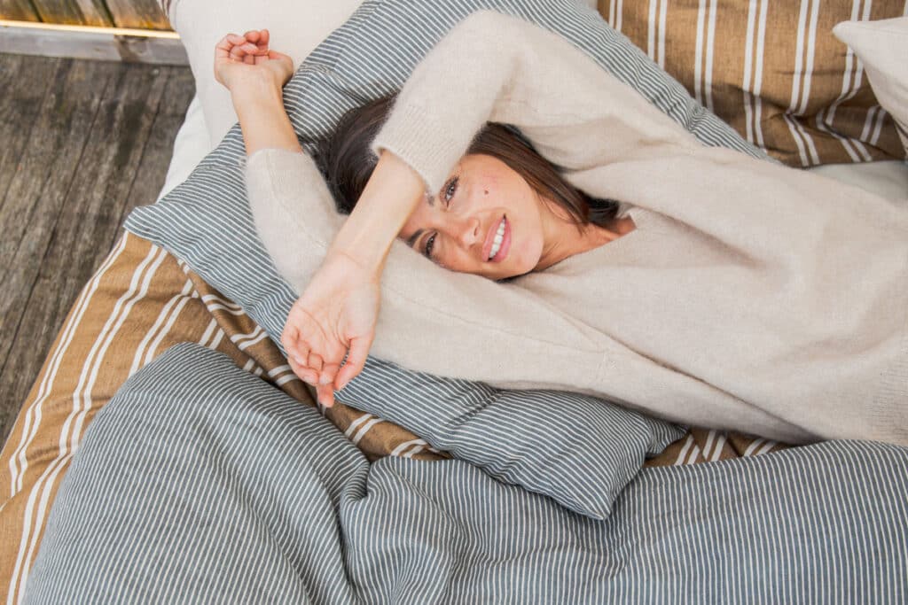 Eine Frau, die auf einem Bett unter einer Decke liegt.