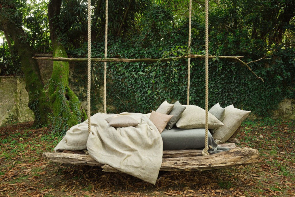 Ein aus einem Baum gemachtes Bett mit einer Decke darauf.