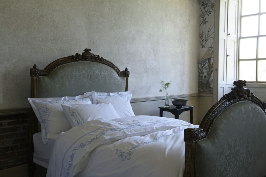 Ein Bett mit weißen Laken und Kissen in einem Zimmer.