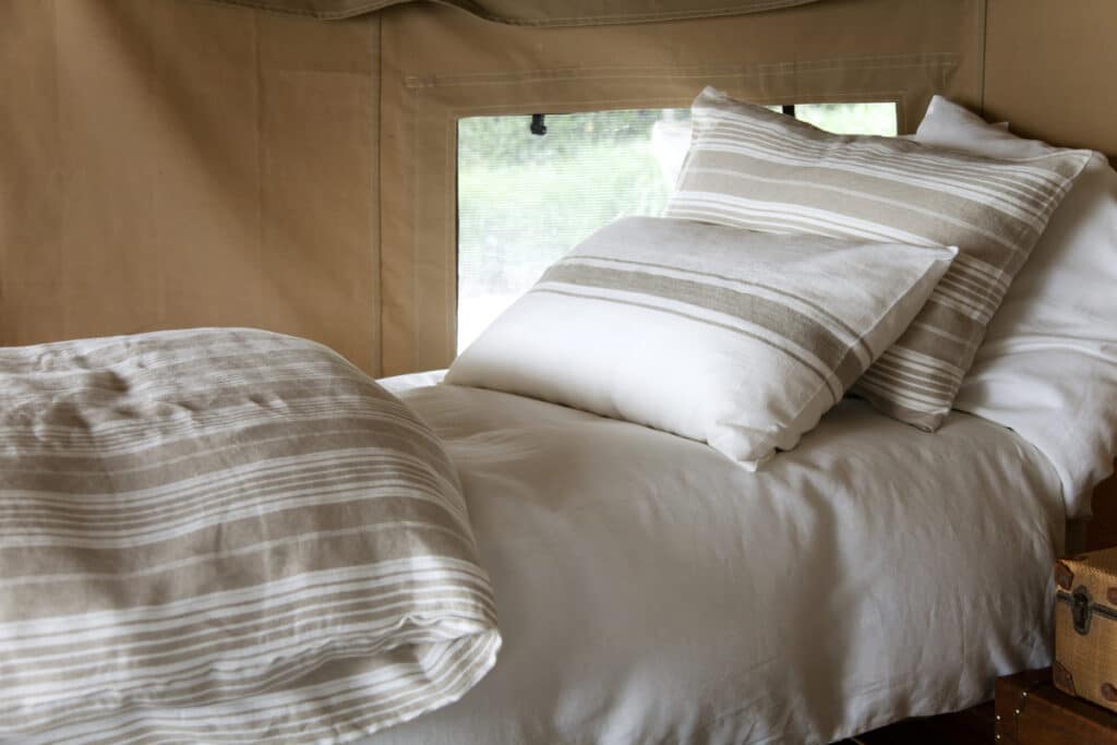 A bed with a white comforter and two pillows.