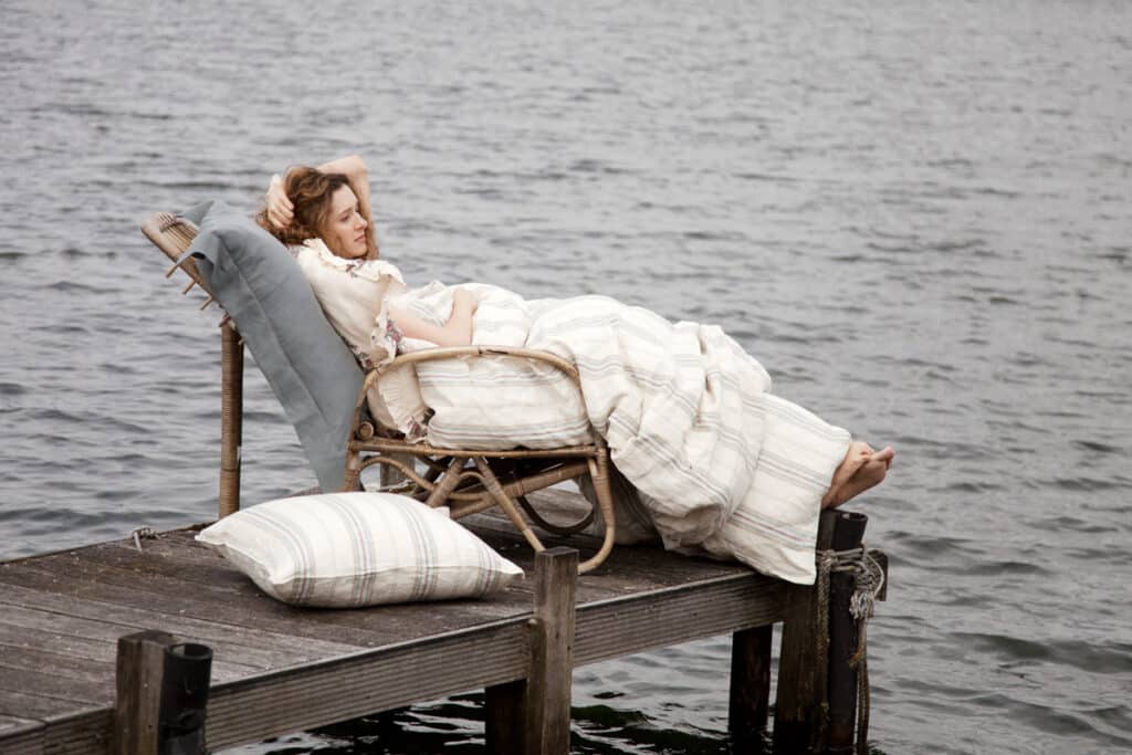 A woman lying on a chair on a jetty.
