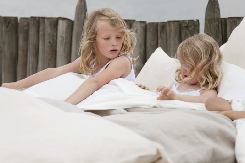 A couple of little girls lying side by side in bed.