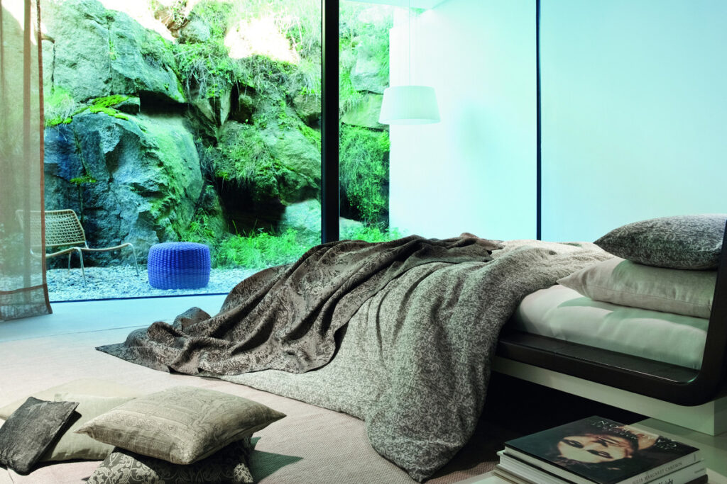Ein Bett, das in einem Schlafzimmer neben einem Fenster steht.