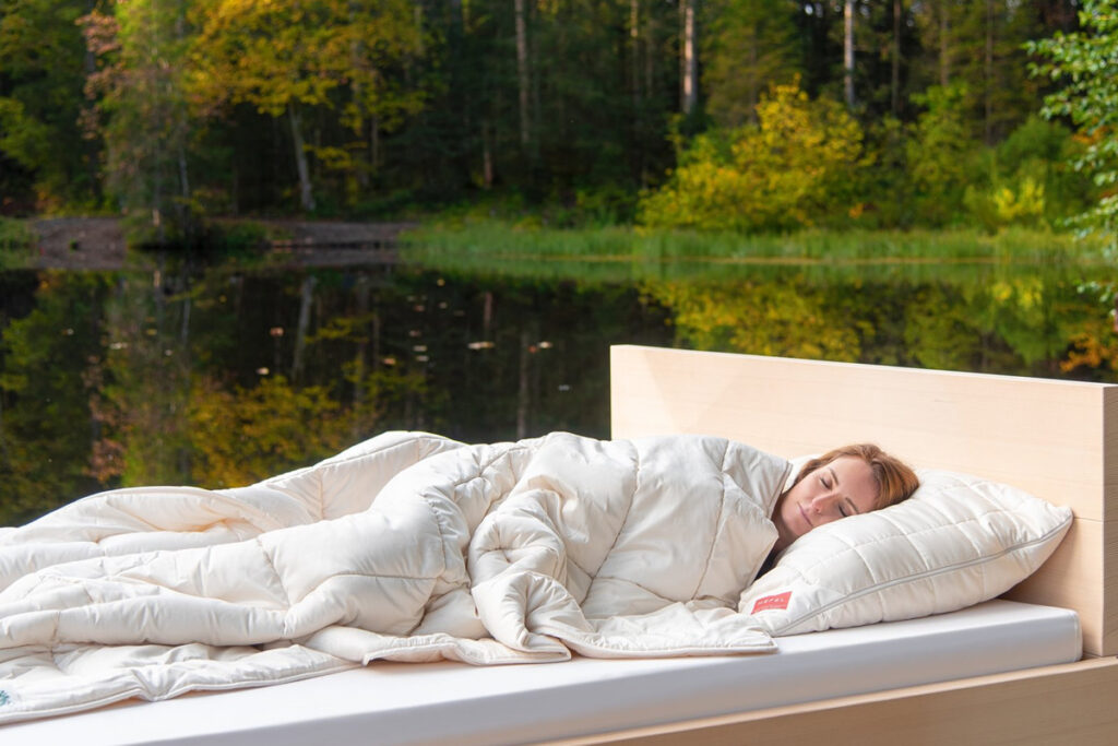 A woman lying in a bed with a white duvet.