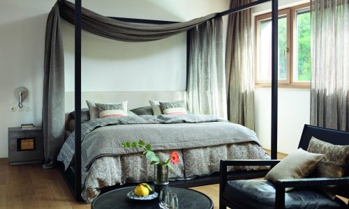 Ein Schlafzimmer mit einem Himmelbett und einem Stuhl.