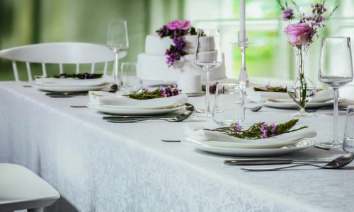 A table is set with white plates and silver cutlery.