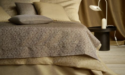 Ein Bett mit einer braunen Decke und Kissen.