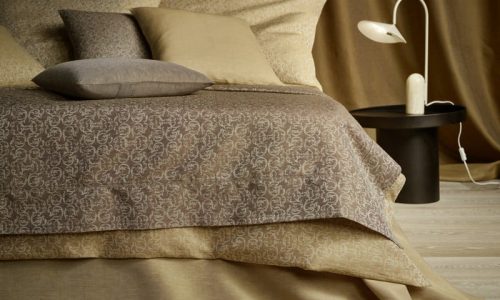 Ein Bett mit einer braunen Decke und Kissen.