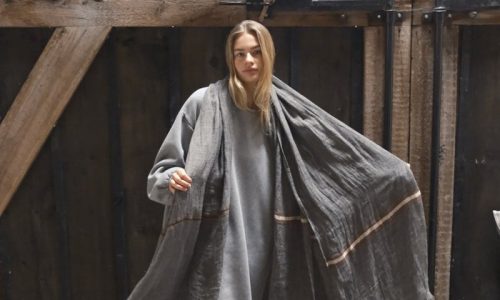 Eine Frau, die auf einer Yogamatte vor einer Scheune steht.