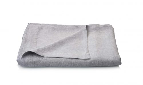 The light gray Caroline linen sheets from Geniksa are neatly folded on a white background, with one corner facing up to show the smooth texture.