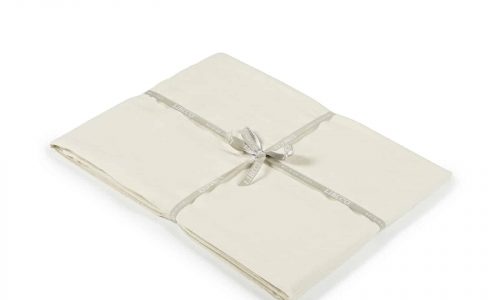 Das Heritage Oyster Bio Leinen Spannbettlaken von Libeco, ein cremefarbenes gefaltetes Bettlaken, das mit einem hellgrauen Band gebunden ist, wird auf weißem Hintergrund gezeigt.