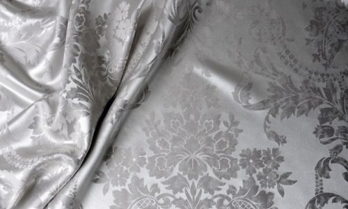 Eine Nahaufnahme eines Bettes mit weißer und grauer Bettdecke.