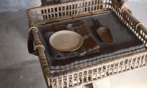 Eine Person, die einen Korbsessel mit einem Teller in der Hand hält.