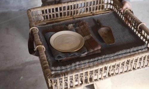 Eine Person, die einen Korbsessel mit einem Teller in der Hand hält.