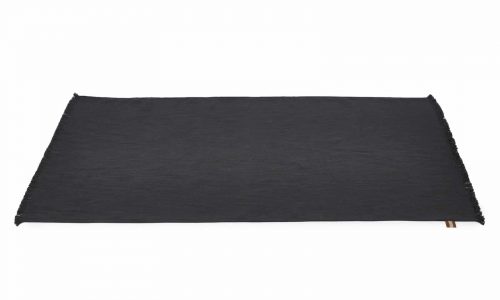 Eine rechteckige, flache, dunkelgraue Matte mit leicht ausgefransten Rändern, die auf einem weißen Hintergrund liegt.