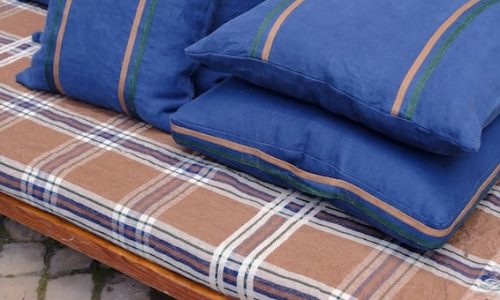 A wooden bench with four cushions on it.