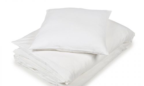 Eine ordentlich gefaltete weiße Bettdecke mit einem passenden Kissen darauf, beides vor einem schlichten weißen Hintergrund - so präsentiert sich die Madison White Farbige Leinen Bettwäsche von Libeco.