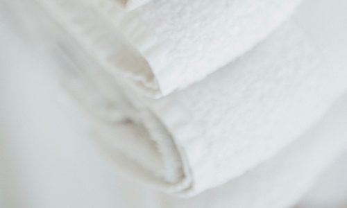 Eine Nahaufnahme von ordentlich gefalteten weißen Handtüchern, die übereinander gestapelt sind und deren weiches, strukturiertes Gewebe zur Geltung kommt.
