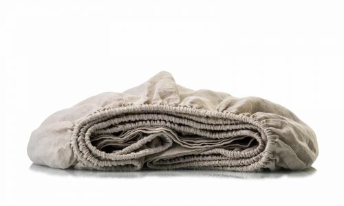 Die Heritage Flax Bio Leinen Spannbettlaken von Libeco sind sauber gefaltet und mit elastischen Rändern versehen. Sie werden auf einer weißen Oberfläche vor einem passenden weißen Hintergrund präsentiert.
