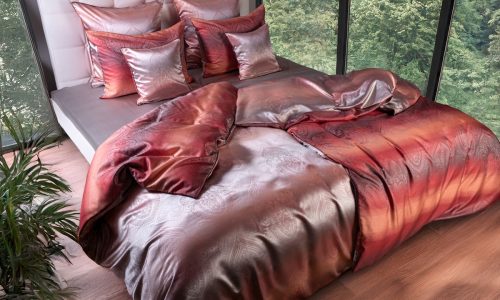 Ein Bett mit einer roten Bettdecke und Kissen.