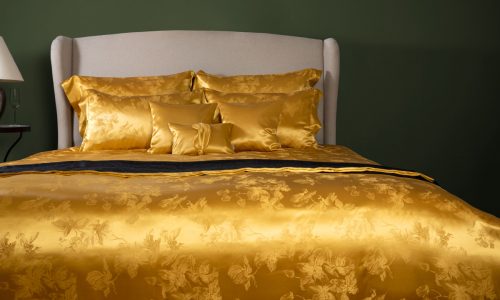 Ein Bett mit einer goldenen Bettdecke und Kissen.