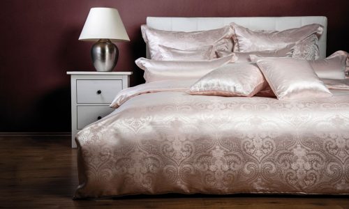 Ein Bett mit einem weißen Kopfteil und einer rosa Bettdecke.