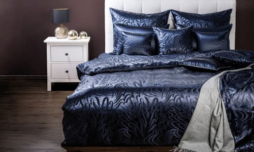 Ein Bett mit einer blauen Bettdecke und Kissen.