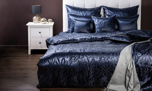 Ein Bett mit einer blauen Bettdecke und Kissen.