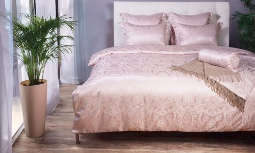 Ein Bett mit rosa Bettdecke und Kissen.