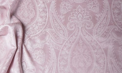 Eine Nahaufnahme eines Bettes mit einer rosa Bettdecke.