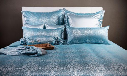 Ein Bett mit einer blauen Bettdecke und Kissen.