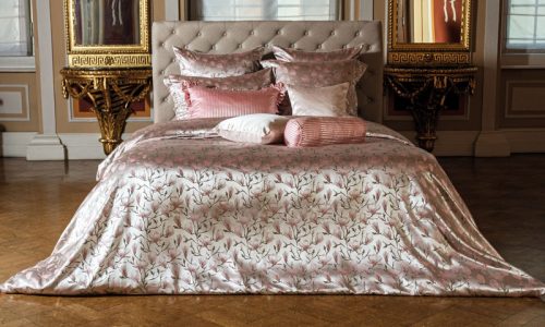 Ein großes Bett in einem Schlafzimmer, das neben zwei Spiegeln steht.